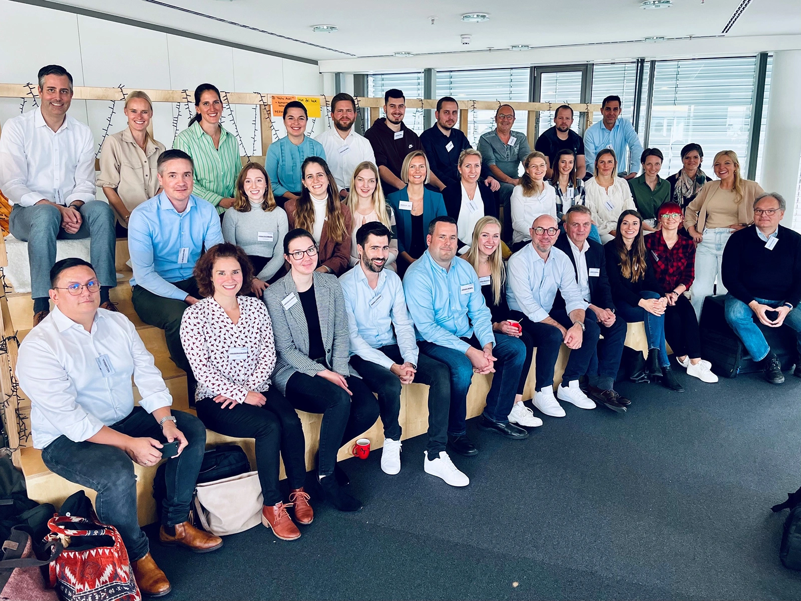 Eine Gruppe von 30 Erwachsenen sitzt und steht in einem hellen Büro für ein Gruppenfoto.