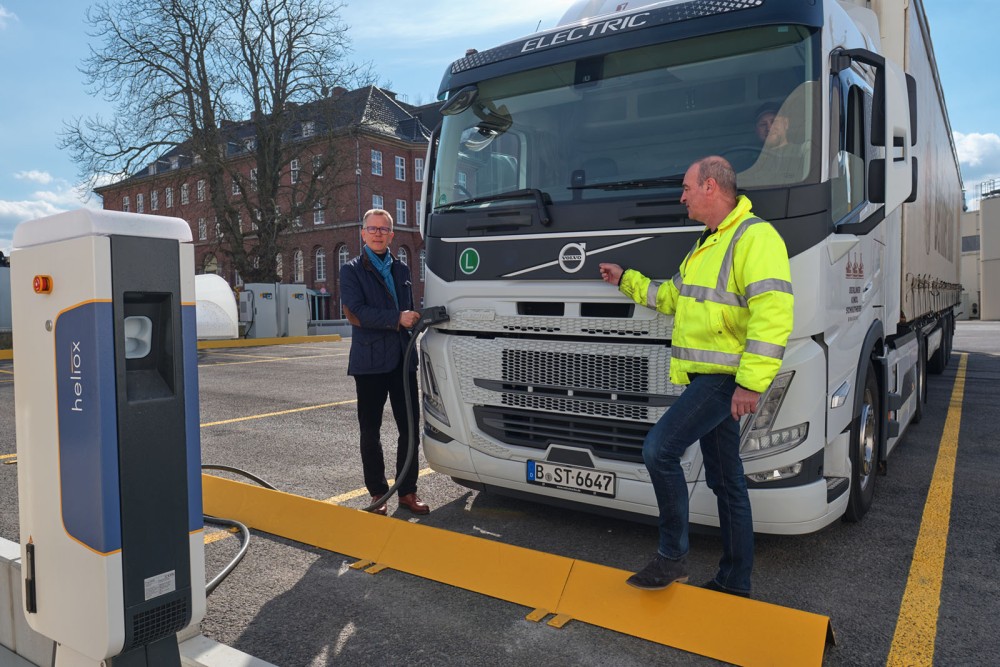 Zwei Männer laden einen elektrischen LKW an einer Ladesäule auf.