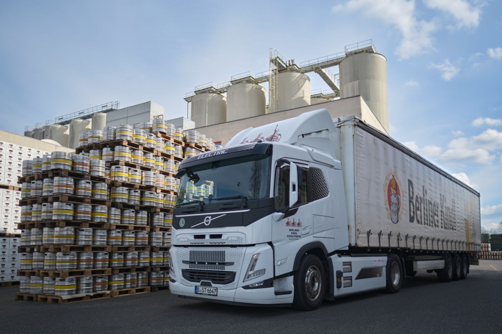 Ein Lastwagen steht vor einem Lager mit mehreren Silos und palettierten Fässern.